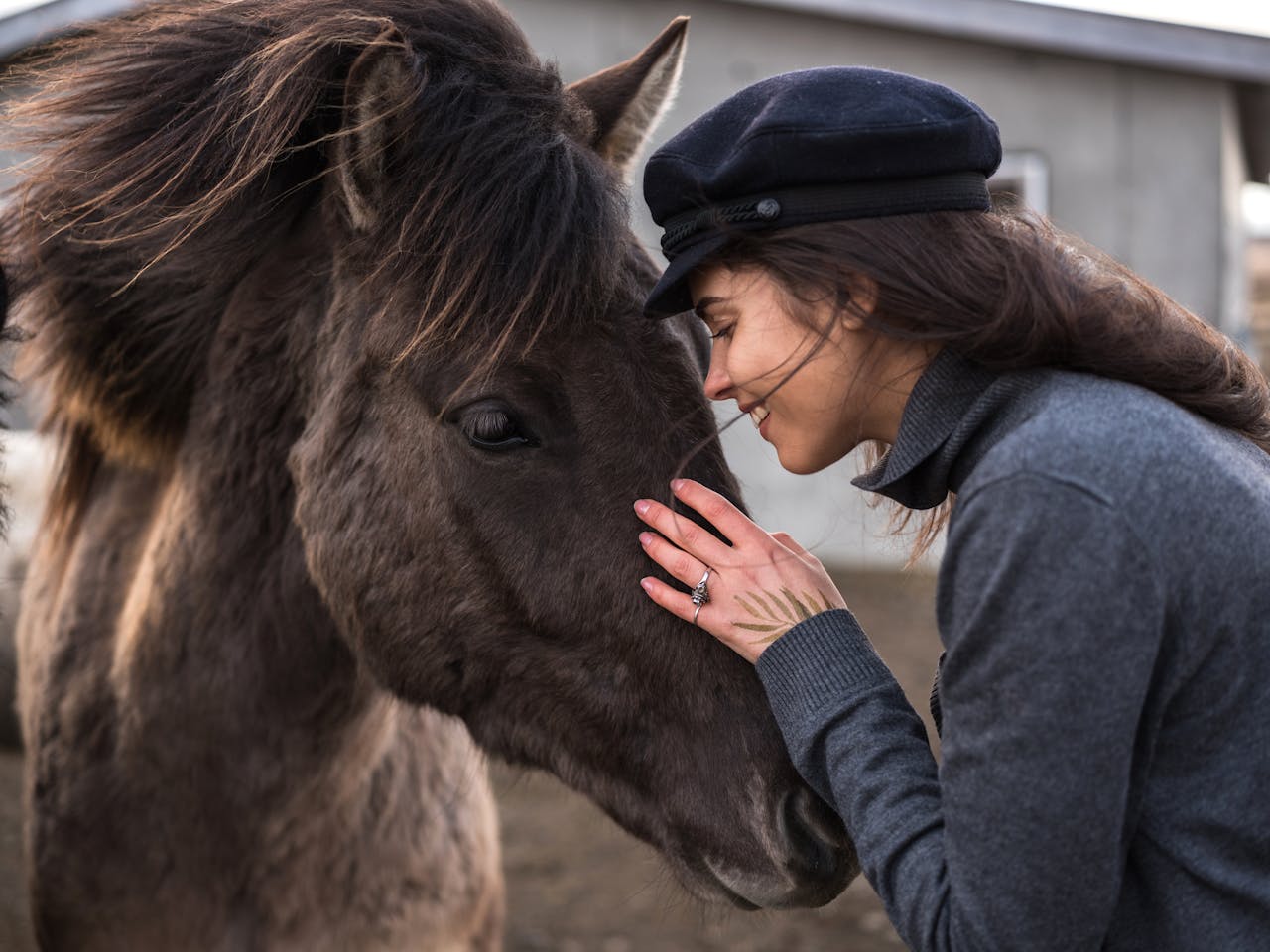 A woman lovingly interacting with a horse in an outdoor setting, showcasing affection and connection.